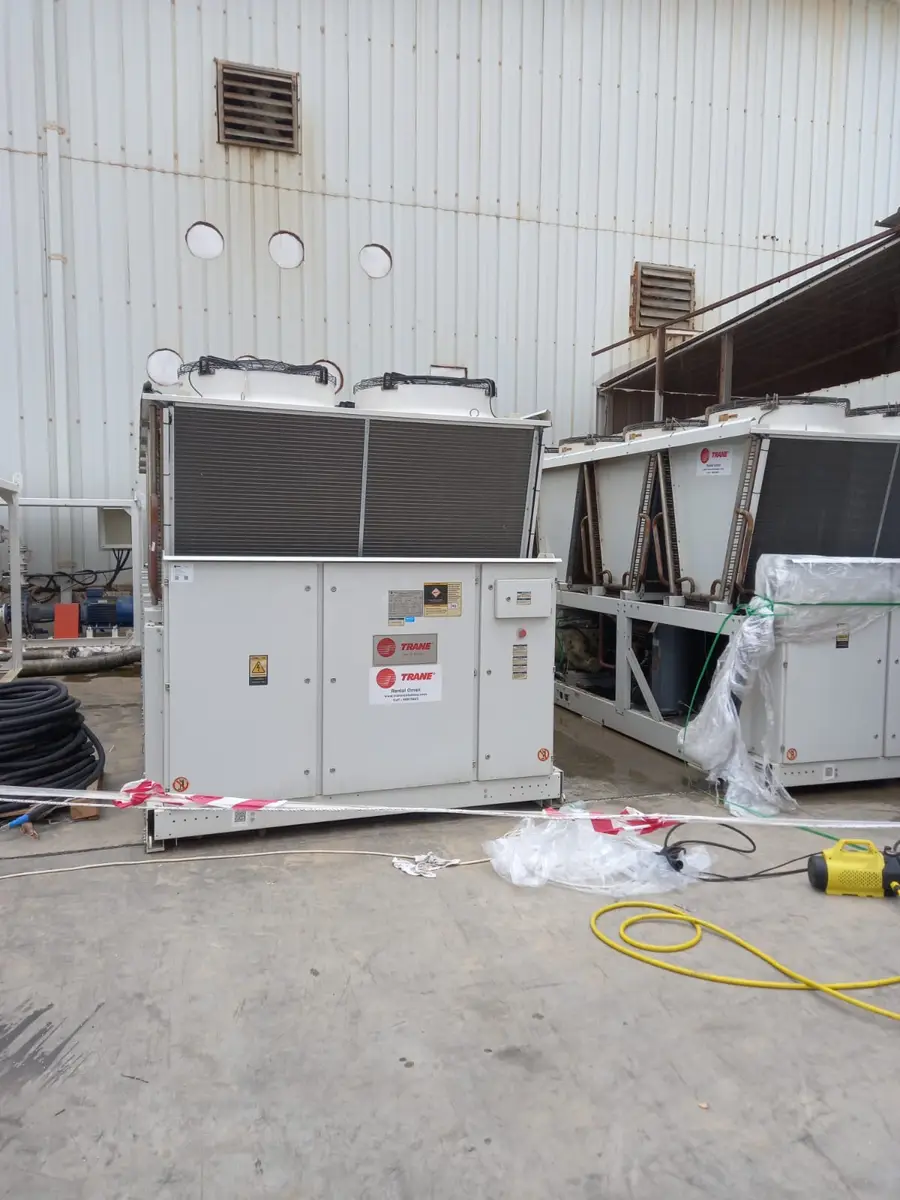 New air-cooled chillers being installed beside a building